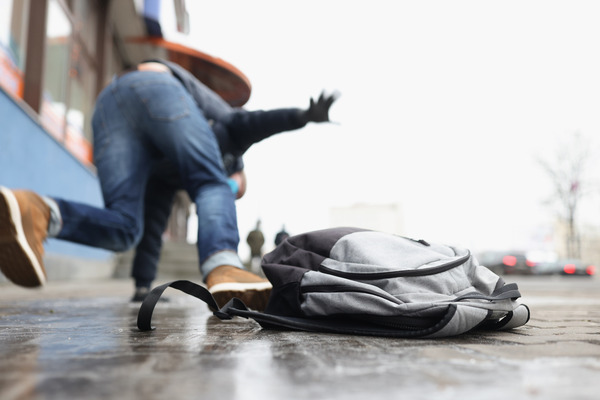 A student slips and falls on a school sidewalk, drops backpack