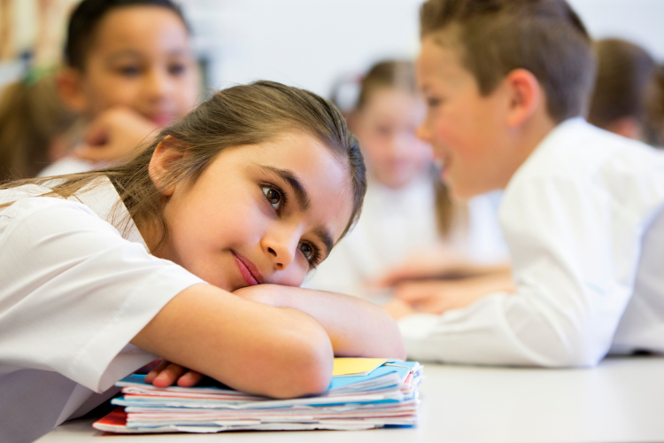 Stock image of private school student with her head resting on her papers.