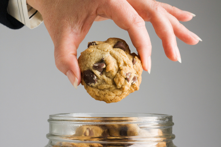A white person's hand going into a cookie jar