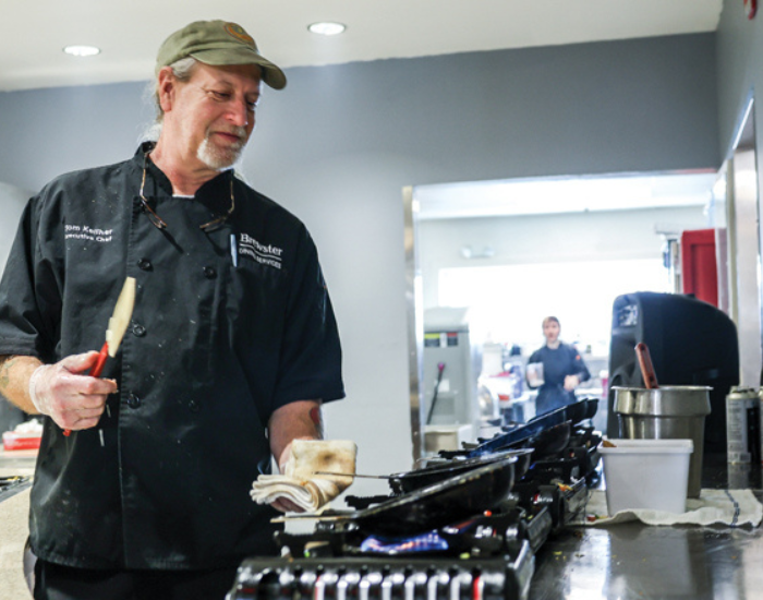 Brewster Academy food provider cooks over a gas range stove