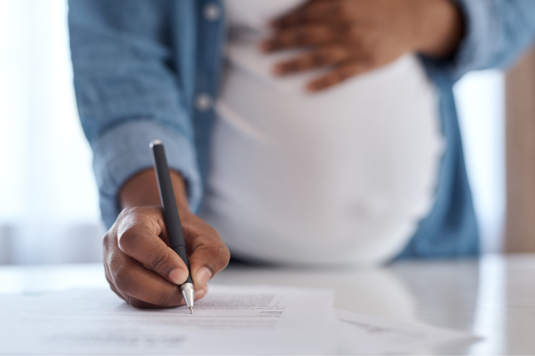 stock image of pregnant person signing paperwork