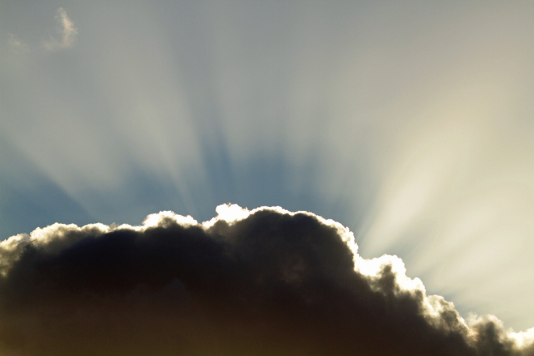 Sunlight streams from behind a dark cloud.